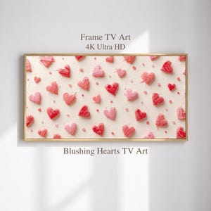 May include: A framed artwork featuring a cream-colored background adorned with numerous textured hearts in shades of pink and red. The artwork is labeled "Frame TV Art 4K Ultra HD" and "Blushing Hearts TV Art".