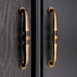 Może przedstawiać: Ręcznie robiony drewniany szyld z napisem "Welcome to our home" w stylu odręcznym. Szyld jest pomalowany na biało z czarnymi literami i postarzanym wykończeniem, odpowiedni do użytku wewnątrz i na zewnątrz.