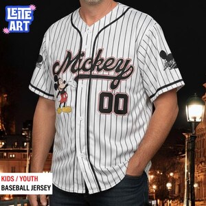 A man wearing a Mickey Mouse baseball jersey with the number 00, standing in front of a nighttime cityscape.