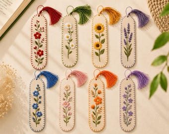 May include: Eight rectangular felt bookmarks with rounded ends, each featuring unique floral embroidery in vibrant colors. Each bookmark is finished with a matching decorative tassel attached to the top, showcasing detailed stitching of various flowers.
