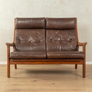 Puede incluir: Un sofá de cuero marrón de dos plazas con estructura de madera. El sofá tiene respaldo alto con dos reposacabezas separados y detalles de botones en los cojines del asiento. Los brazos y patas de madera son de color marrón medio.