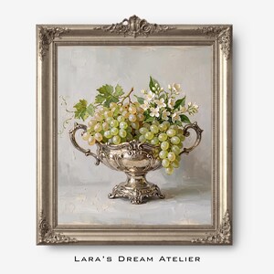 Puede incluir: Pintura de naturaleza muerta enmarcada con una fuente de plata rebosante de uvas verdes y flores blancas. La pintura tiene un fondo gris claro y está enmarcada en un marco plateado ornamentado. El texto "Lara's Dream Atelier" está en la parte inferior.