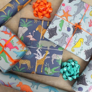 May include: Several wrapped gifts with colorful animal and sea creature patterns. The wrapping paper features illustrations of dinosaurs, lions, giraffes, and hammerhead sharks. Each gift is tied with ribbons and bows in various colors, including orange and teal.
