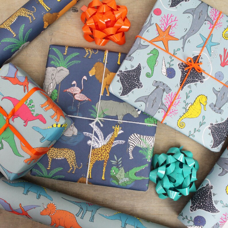 May include: Several wrapped gifts with colorful animal and sea creature patterns. The wrapping paper features illustrations of dinosaurs, lions, giraffes, and hammerhead sharks. Each gift is tied with ribbons and bows in various colors, including orange and teal.