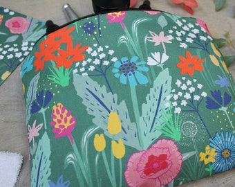 Op de afbeelding: Een groene toilettas met een bloemenprint met kleurrijke bloemen, bladeren en stelen. De tas is gemaakt van stof en heeft een ritssluiting.