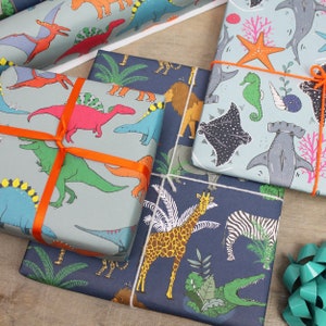 May include: Several wrapped gifts with colorful patterned paper. One features dinosaurs, another has sea creatures, and a third showcases jungle animals. Each is tied with orange or white ribbon. The gifts are arranged on a wooden surface.