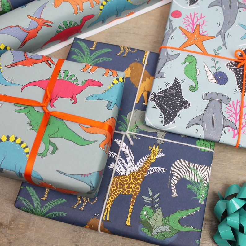 May include: Several wrapped gifts with colorful patterned paper. One features dinosaurs, another has sea creatures, and a third showcases jungle animals. Each is tied with orange or white ribbon. The gifts are arranged on a wooden surface.