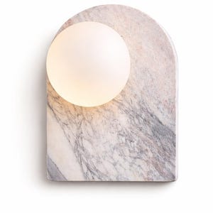 May include: A modern wall sconce featuring a marble base with a rounded top and a frosted glass globe. The marble has a gray and pink veining pattern. The globe is lit, emitting a soft glow.