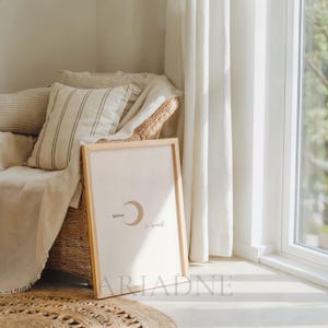 Peut inclure: Un cadre en bois clair avec l'inscription « Believe in yourself » et un croissant de lune brun clair. L'impression est présentée dans une pièce lumineuse et aérée, avec un fauteuil en osier et des coussins aux tons neutres.