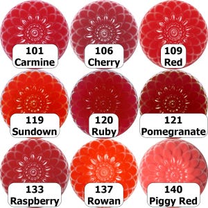 May include: Nine spherical objects in shades of red, from carmine to piggy red, are arranged in a grid. Each sphere has a detailed, flower-like pattern. White labels below each sphere display color names and numbers.