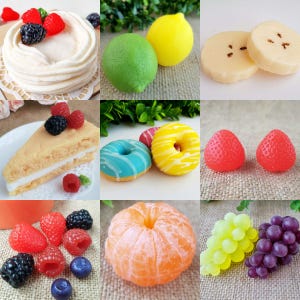 May include: A collage of colorful, artificial food items. Includes a layered cake topped with berries, a slice of cake, two donuts with icing, two lemons, a lime, two banana slices, two strawberries, a peeled orange, a cluster of green grapes, and a cluster of purple grapes.