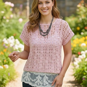 Könnte beinhalten: Ein hellrosa, kurzärmeliges Häkeltop mit quadratischem Ausschnitt. Das Top wird mit einem weißen Spitzenunterhemd und dunkelblauen Jeans kombiniert. Eine dunkelgraue Halskette wird getragen. Der Hintergrund zeigt einen Garten mit Blumen und einer Steinmauer.