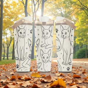 Peut inclure: Trois bouteilles d'eau isolées blanches avec une illustration de chat. Les bouteilles ont une poignée et un couvercle beiges. Le motif de chat est noir et blanc, avec des empreintes de pattes et des étoiles. Le mot "owala" est imprimé sur le fond.