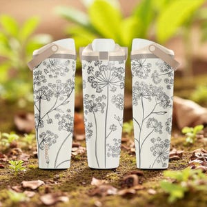 Peut inclure: Trois bouteilles d'eau crème avec un motif floral. Chaque bouteille a une poignée et un couvercle beiges. Le motif floral est dans les tons de gris. Les bouteilles sont sur un lit de feuilles brunes et de plantes vertes.
