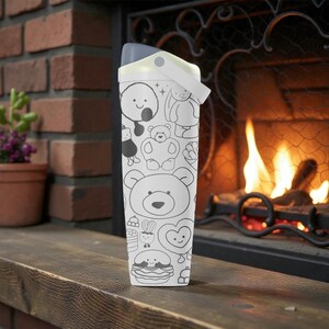 May include: A white water bottle with a gray lid and handle, decorated with black and white cartoon illustrations of bears, bunnies, and other cute characters. The bottle is standing on a wooden surface in front of a brick fireplace.