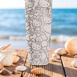 May include: A white tumbler featuring a black and white Hello Kitty design. The tumbler is covered in illustrations of Hello Kitty with hearts and bows. The tumbler is on a wooden surface with seashells and the ocean in the background.