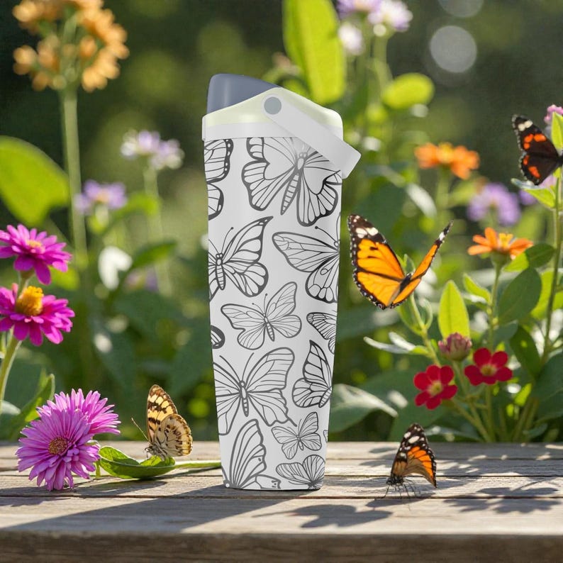 May include: A white water bottle with a gray lid and a butterfly pattern. The bottle is cylindrical and features a repeating design of black and white butterflies. The background includes colorful flowers and butterflies.