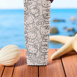 May include: A white tumbler featuring a repeating black and white pattern of Hello Kitty characters in various poses. The tumbler is set on a wooden surface with a seashell and starfish in the background.