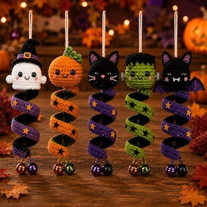 May include: Five crocheted Halloween hanging ornaments featuring a ghost with a witch hat, a pumpkin, a black cat, a green monster, and a bat. Each figure is attached to a spiraling tail decorated with stars and two small metal jingle bells.