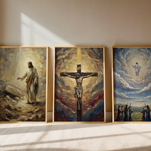 Op de afbeelding: Drie religieuze schilderijen met een lijst. De eerste toont een figuur in witte gewaden, de tweede een kruisiging en de derde een figuur die naar de hemel opstijgt. Alle schilderijen hebben gouden lijsten en worden tentoongesteld op een licht oppervlak.