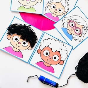 Könnte beinhalten: Eine Sammlung quadratischer Karten mit Cartoon-Gesichtern mit großen Augen und rosa Nasen. Eine Karte zeigt ein Gesicht mit befestigtem schwarzem Wollhaar. Andere Karten zeigen illustrierte Frisuren, darunter weißes lockiges Haar und eine rosa Brille. Ein blauer Klebestift ist vorhanden.