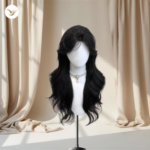 May include: A black wig with long, wavy layers is displayed on a mannequin head. The wig has a side parting and a natural-looking hairline. A pearl necklace with a pendant adorns the mannequin. The background includes beige curtains.