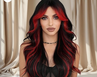 May include: A woman with long, wavy black hair with striking red highlights around the face. The hair falls over the shoulders. She wears a black top and a delicate gold necklace. The background features a neutral-toned curtain.
