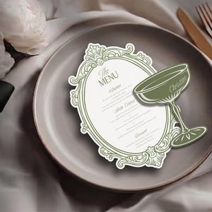 May include: An oval-shaped menu card with a sage green ornate border and a matching sage green cocktail glass cutout attached to the side. The menu features the text The MENU, Starter, Main Course, and Dessert with the name Christine on the glass.