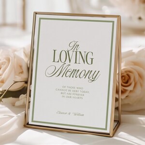 May include: A vertical rectangular sign in a thin gold metal frame featuring the text In Loving Memory of those who cannot be here today, but are forever in our hearts, with the names Eleanor & William printed in dark green on a white background.