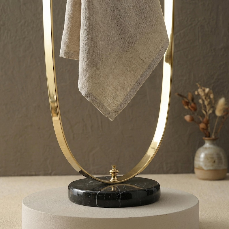 Portasciugamani in ottone lucido, base in marmo nero, accessorio moderno per il bagno. immagine 2