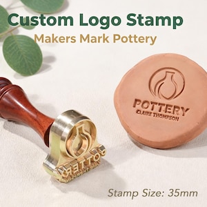 May include: A custom brass logo stamp with a dark wooden handle, featuring a 35mm diameter head. The stamp displays a pottery vessel icon and the text POTTERY CLAIRE THOMPSON. A terracotta clay disc shows the embossed impression of the stamp design.