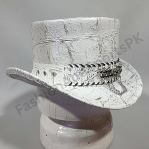 May include: White top hat with a textured, crocodile-like pattern. The hat features a decorative band with black stitching, silver-toned embellishments, and a chain. The hat is displayed on a white stand.