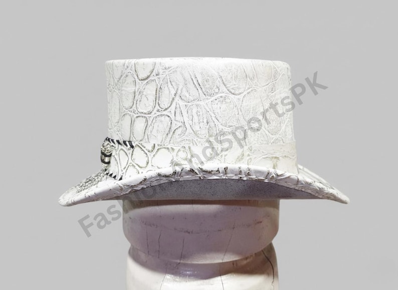 May include: White top hat with a textured, crocodile-like pattern. The hat features a black and white band around the base and a wide brim. The hat is displayed on a white form against a light gray background.