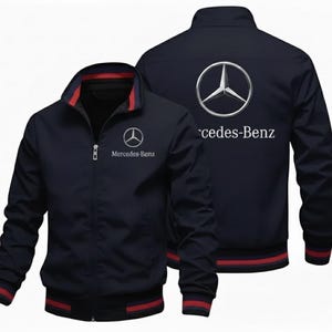 Può includere: Giacca blu navy con zip con il logo Mercedes-Benz sul petto e sulla schiena. La giacca ha un collo alto con finiture rosse e nere. Il logo e il testo Mercedes-Benz sono bianchi.
