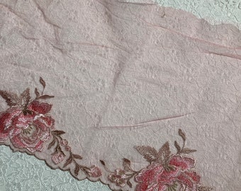 May include: Pink sheer fabric with a delicate floral lace trim. The lace features pink and brown embroidered flowers.