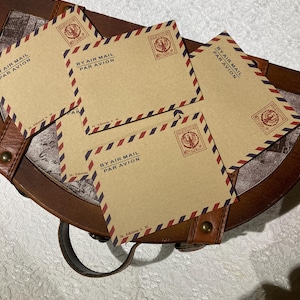 May include: A collection of tan envelopes featuring a red and blue striped border. Each envelope is printed with the text BY AIR MAIL PAR AVION and includes a red stamp-like emblem with an eagle design in the top right corner.