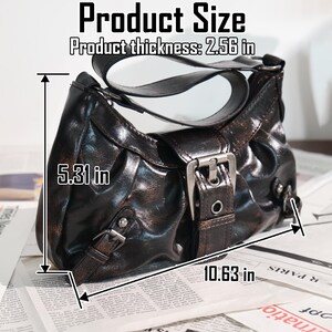 May include: A brown handbag with a shiny finish, featuring a buckle closure and a shoulder strap. The bag measures 10.63 inches wide, 5.31 inches high, and 2.56 inches thick. The text "Product Size" is visible.
