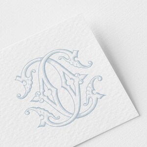 Op de afbeelding: Een lichtblauw monogramontwerp met de verweven letters "J" en "D" in een elegante, sierlijke stijl. Het ontwerp is gedrukt op een getextureerd wit papier, wat een klassieke en verfijnde uitstraling creëert, geschikt voor briefpapier of uitnodigingen.