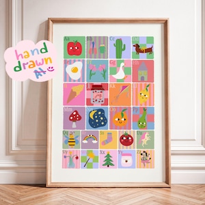 May include: A framed alphabet poster featuring a grid of colorful squares, each displaying a letter from A to Z paired with a corresponding illustration like an apple, cactus, dog, egg, jam, and zebra, with the text hand drawn in a cloud.