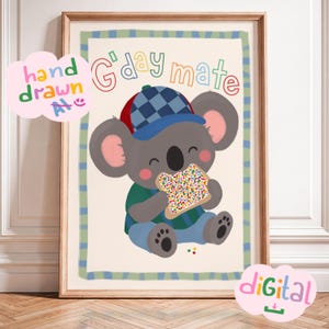 Op de afbeelding: Een ingelijste kunstprint met een grijze koala die een blauw-rode geruite honkbalpet, een groen shirt en een blauwe broek draagt. De koala eet een stuk brood met kleurrijke hagelslag. De tekst G'day mate staat bovenaan de afbeelding.