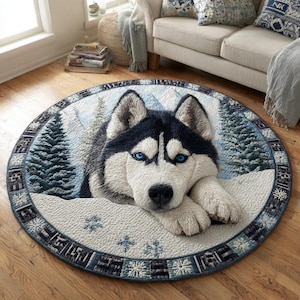 Può includere: Un tappeto rotondo con un'immagine dettagliata di un cane husky con occhi blu, ambientato in un paesaggio montano innevato. Il tappeto ha un bordo decorativo con motivi a fiocco di neve e geometrici. Il pelo del cane è bianco e nero.