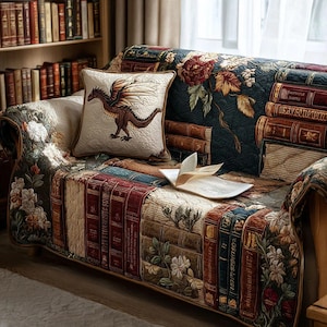 May include: A decorative sofa with a quilted cover featuring a design of stacked books and floral patterns. A square pillow with a dragon illustration rests on the sofa. An open book lies on the sofa, and a bookshelf is in the background.