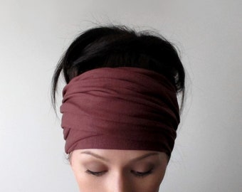 May include: A wide, dark maroon headband made of soft, stretchy fabric. The accessory features a gathered, multi-layered design that wraps horizontally around the head, creating a series of horizontal folds and a smooth, fitted appearance.