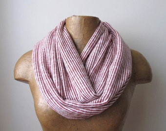 May include: A red and white striped infinity scarf made of a soft, knit fabric.