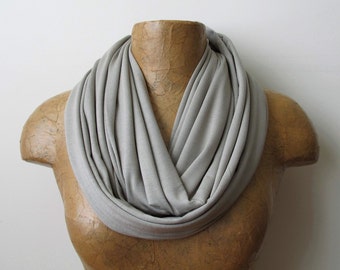 May include: A gray infinity scarf made of soft fabric. The scarf is draped around a mannequin's neck.