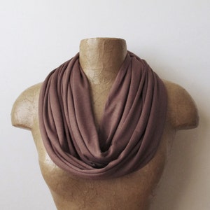 May include: A brown infinity scarf made of soft, stretchy fabric. The scarf is draped around a mannequin's neck.