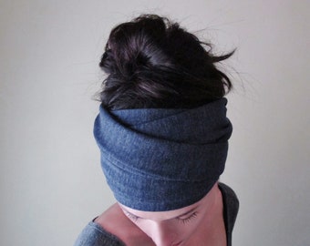 May include: A dark blue denim-textured fabric headband featuring a wide, multi-layered wrap design that encircles the head. The material has a subtle heathered appearance with visible cross-hatched weave patterns throughout the entire surface.