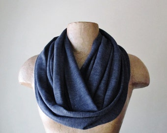 May include: A dark blue infinity scarf made of a soft, stretchy fabric. The scarf is folded and draped around a mannequin's neck.