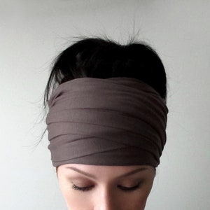 May include: A brown fabric headband worn on a person's head. The headband is folded and tied in a knot at the top of the head.