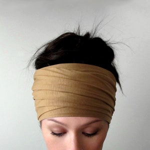 May include: A brown fabric headband worn on a person's head. The headband is folded and tied in a knot at the top of the head.